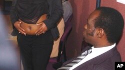 L'archevêque Gilbert Deya, à droite, regarde une femme enceinte Deonna Dakkins-Scott, montrant son ventre à des journalistes lors d'une conférence de presse à Glasgow, Écosse, 29 septembre 2004. 