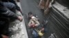 Syria Civil Defense members help an unconscious woman from a shelter in the besieged town of Douma, Eastern Ghouta, Damascus, Syria, Feb. 22, 2018. 