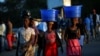 FILE - Women carry baskets with food items on their heads at a market in Blantyre, Malawi, July 10, 2017. 