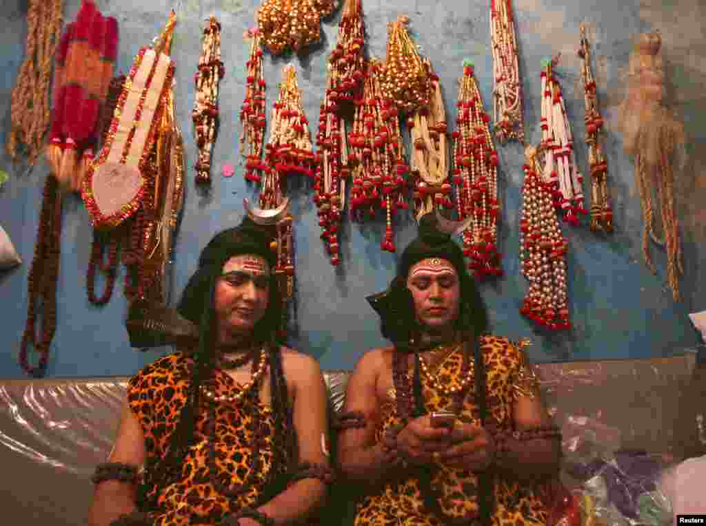 Seniman dengan kostum sebagai Dewa Shiwa membaca pesan di telpon seluler sambil bersiap-siap ikut dalam prosesi keagamaan sebelum berlangsungnya Festival Mahashivratri di Jammu, Nepal. Perempuan Hindu di seluruh negeri itu merayakan Mahashivratri, yaitu ulang tahun pernikahan Dewa Shiwa, supaya suami mereka dikaruniai umur panjang.