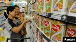 Seorang penjaga toko (belakang) di sebuah supermarket di Hefei, provinsi Anhui, membantu seeorang konsumen dalam memilih produk susu bubuk Dumex (5/8).