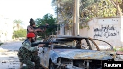 Pasukan pro-pemerintah Libya membidik senjata mereka dalam bentrokan dengan Dewan Shura Revolusioner Libya, aliansi man tan pemberontak anti-Gadhafi, yang bergabung dengan kelompok Islamis Ansar al-Sharia, di Benghazi, 28 Desember 2014.