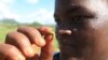 FILE - A woman holds an armyworm she found feeding on her maize crop at a farm in Zimbabwe, Feb. 14, 2017.