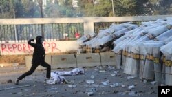 A student protester throws a rock at riot police officers during a clash in Jakarta, Indonesia, Monday, Sept. 30, 2019. Thousands of Indonesian students resumed protests on Monday against a new law they say has crippled the country's anti-corruption agency, with some clashing wit