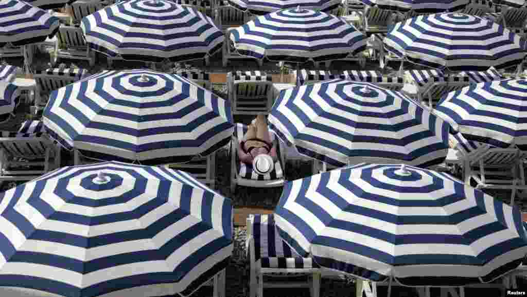 ភ្ញៀវទេសចរ​ម្នាក់​កំពុង​ហាលថ្ងៃនៅ​ឆ្នេរ Promenade Des Anglais ក្នុង​រដូវ​ក្តៅ​ទីក្រុង​ Nice ប្រទេស​បារាំង។