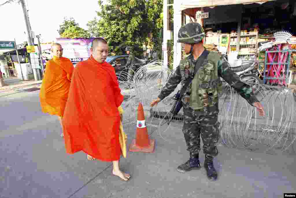 Dua Biksu Buddha berjalan tanpa alas kaki melewati pos penjagaan dekat kemah demonstran &quot;Kaos Merah&quot; pro-pemerintah Thailand di provinsi Nakhon Pathom, di pinggiran kota Bangkok, 22 Mei 2014.