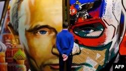 Un homme regarde un tableau représentant le président russe Vladimir Poutine à l'exposition "SUPERPUTIN" au musée de l'UMAM à Moscou le 6 décembre 2017