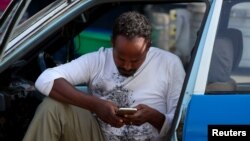 ፎቶ ፋይል: ታክሲ አሽከርካሪው ደንበኛውን በመጠበቅ ላይ እያለ ስማርት ስልኩን እየነካካ