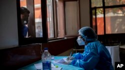 在印度首都新德里，一位医护人员正在记录新冠患者的名字。