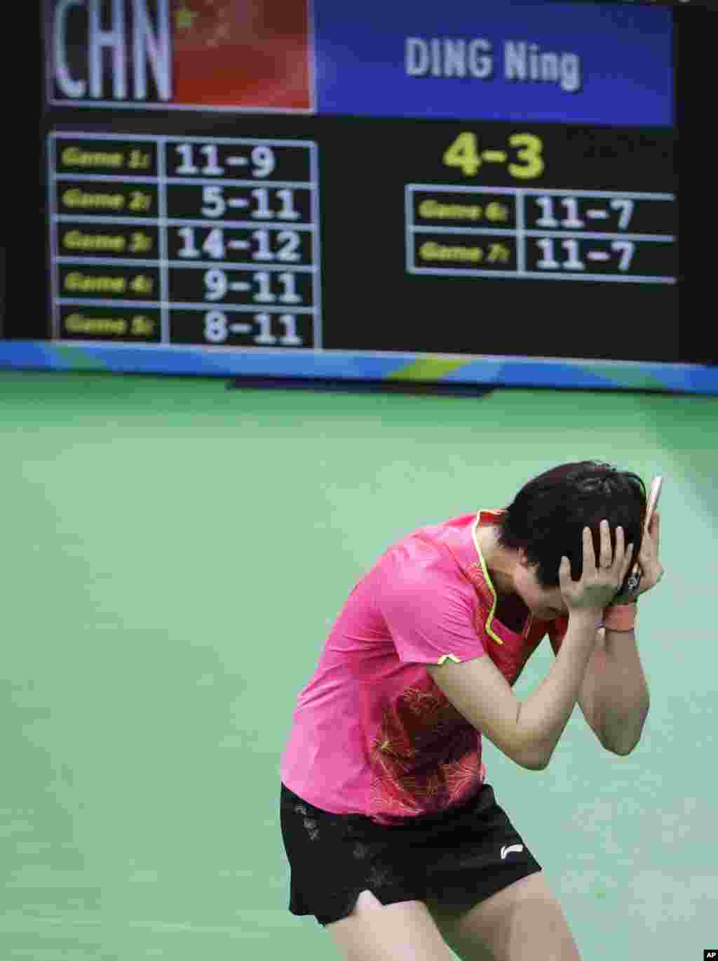 Ding Ning dari China memegang kepalanya setelah mengalahkan atlet senegaranya, Li Xiaoxia, dan meraih medali emas dalam tenis meja perseorangan putri (10/8). (AP/David Goldman)