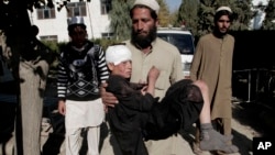 Seorang pria menggendong anak lelaki yang terluka ke rumah sakit menyusul ledakan dua bom di distrik Achin, Jalalabad, sebelah timur Kabul, Afghanistan, November 2013. 