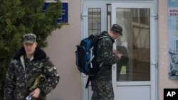 乌克兰空军军官带着背包离开他们在克里米亚新菲罗波尔城外的基地。（2014年3月20日）