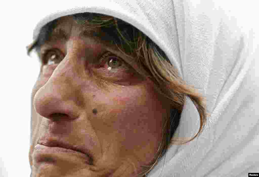 Seorang wanita mengamati layar raksasa yang menayangkan saat-saat terakhir Paus Benediktus XVI meninggalkan kota Vatikan. 