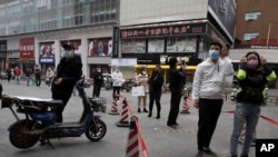 Residents wearing masks to protect against the spread of the coronavirus line up to enter a supermarket in Wuhan in central China's Hubei province on Friday, April 3, 2020. Chinese leaders are trying to revive the economy, but local officials under…