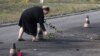 A woman puts flower on the ground in the spot where shell landed killing several people, in Sartana, on the outskirts of the town of Mariupol, eastern Ukraine, Oct. 15, 2014.