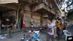 Warga memeriksa lokasi ledakan bom dekat restoran dan kedai kopi yang penuh pelanggan di daerah Karradah yang sibuk di Baghdad, Minggu, 3 Mei 2015. (AP Photo/Hadi Mizban)