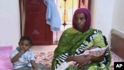 FILE - Meriam Ibrahim, sitting next to Martin, her 18-month-old son, holds the newborn daughter she gave birth to in jail in May at a prison in Khartoum, Sudan. 