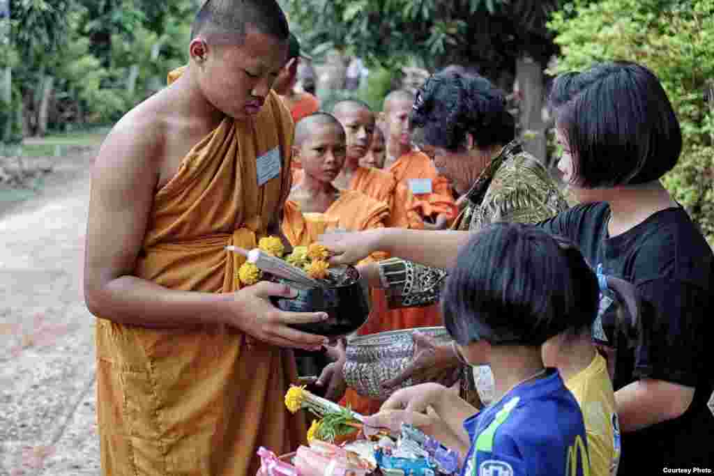 Beberapa pemuda yang baru saja menjadi Pendeta Budha mendapatkan makanan mereka dari warga desa di Thailand.