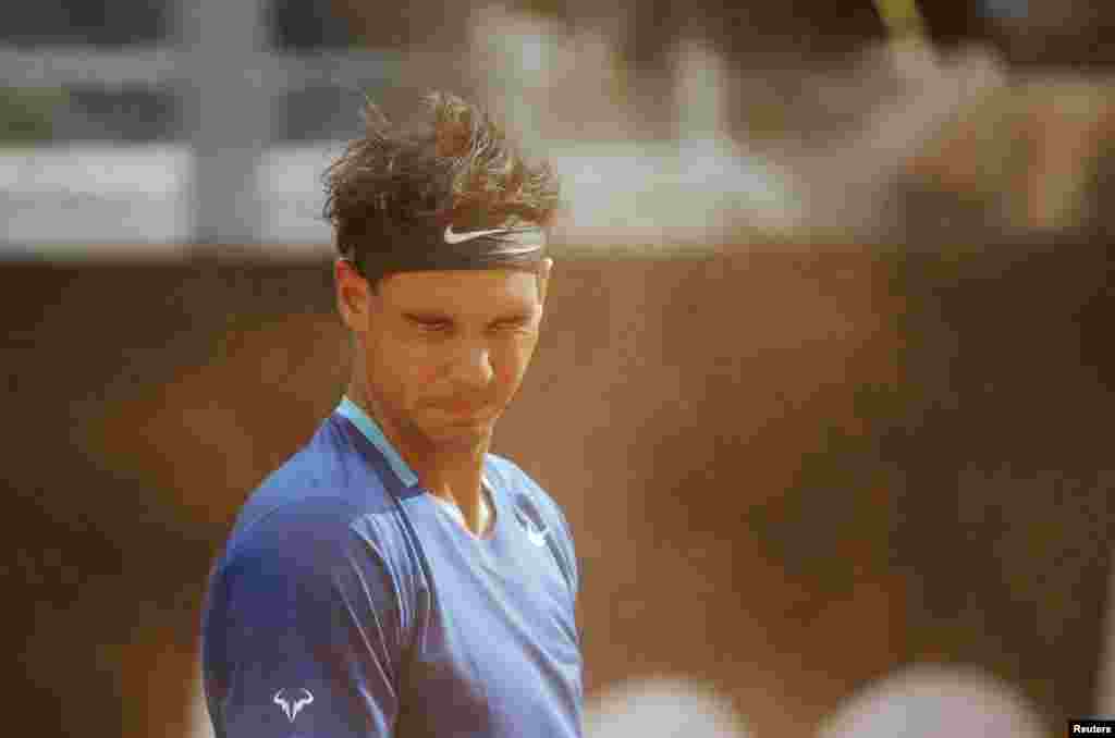 Rafael Nadal of Spain reacts as he takes shelter from sand blown by the wind during the men&#39;s singles match against Mikhail Youzhny of Russia at the Rome Masters tennis tournament, Italy.