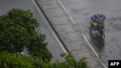 A vendor protects his merchandise with an umbrella as he rides his bicycle under a heavy rain in downtown Rio de Janeiro, Brazil, on March 22, 2024.