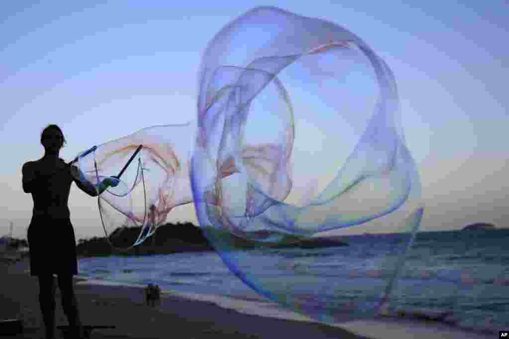 Seniman jalanan Jerman Florian Timm, 27, membuat gelembung sabun raksasa di pantai Ipanema di Rio de Janeiro, Brazil (4/6).
