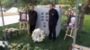 2019年10月18日，赵紫阳夫妇墓碑前摆放着出席骨灰安葬仪式的亲友们献的鲜花。赵紫阳之子赵二军（右）立于碑前。（美国之音艾伦拍摄）