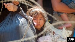 Para migran menunggu polisi perbatasan di Makedonia membolehkan mereka memasuki pagar perbatasan antara Yunani dan Makedonia (28/8).