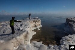 A young boy tosses a chunck of snow into Lake Michigan Wednesday, Jan. 30, 2019 in Milwaukee. Temperatures were sub-zero and wind chills were -50 degrees. (AP Photo/Jeffrey Phelps)