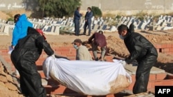 Des fossoyeurs dans un cimetière près de la ville côtière de Sfax, portent des tenues de protection lors de l'enterrement de l'un des 52 migrants africains, décédé en mer lorsque leur bateau a chaviré près des îles Kerkennah en Tunisie, le 15 juin 2020.