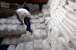FILE - Men load rice bags to a ship for export at a rice processing factory in Vietnam's southern Mekong delta, Vietnam July 6, 2017.