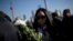 A woman offers flowers during a memorial ceremony in memory of people who were killed in a stampede incident during a New Year's celebration, on the Bund in Shanghai, Jan. 1, 2015. 