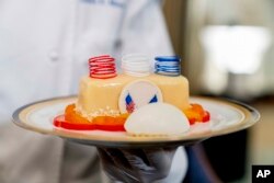 White House executive pastry chef Susie Morrison, right, holds a dish during a media preview for the State Dinner with President Joe Biden and French President Emmanuel Macron in the State Dining Room of the White House in Washington, Wednesday, Nov. 30, 2022. The dinner will include a butter poached Maine lobster, beef with shallot marmalade, American artisanal cheeses, and an orange chiffon cake for desert. (AP Photo/Andrew Harnik)