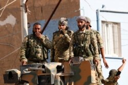 Members of Syrian National Army, known as Free Syrian Army, stand on top of an armored vehicle in the Turkish border town of Ceylanpinar in Sanliurfa province, Turkey, Oct. 11, 2019.