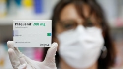 A pharmacist displays a box of Plaquenil antimalarial tablets in this illustration picture