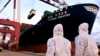 身穿防护服的中国海关人员在山东省青岛港检查一艘货轮。（2020年11月16日）