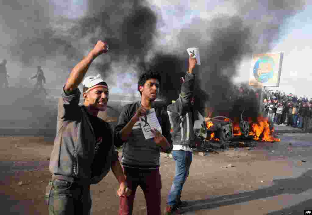 Egyptian protesters shout slogans in front of burning cars set on fire during a demonstration calling for a &quot;No&quot; vote in a referendum on a new constitution in the coastal city of Alexandria, Dec. 14, 2012.