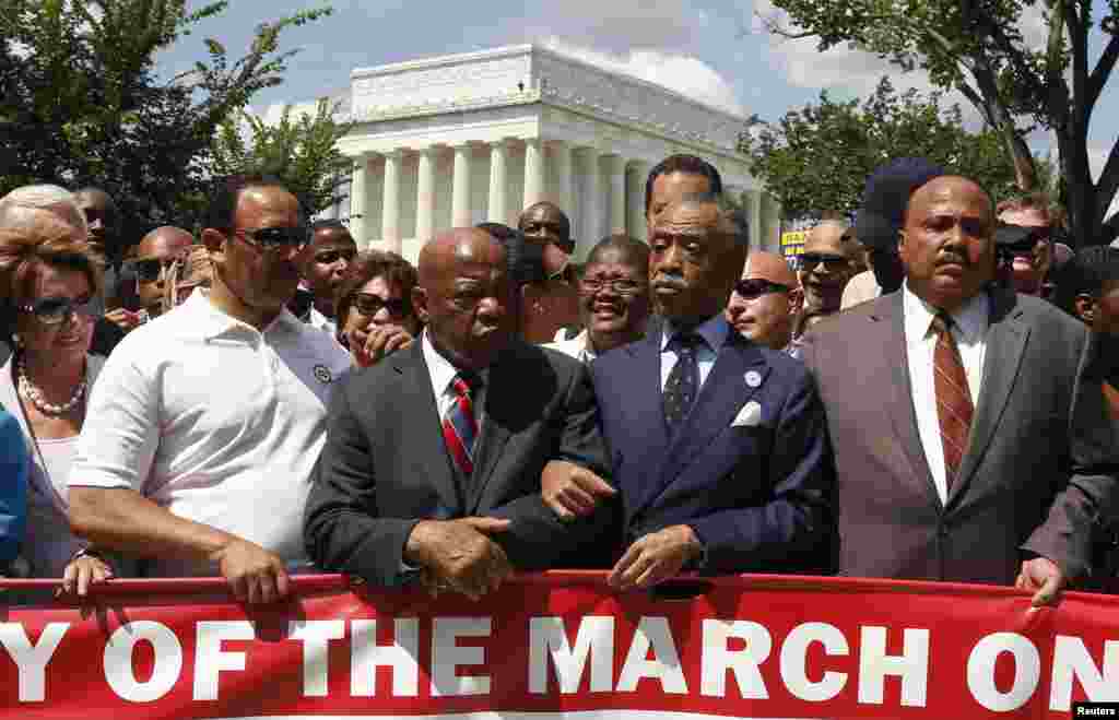 Pendeta Al Sharpton (kedua dari kiri) bergandengan tangan dengan legislator John Lewis dan Martin Luther King III (kanan) saat mereka mulai berpawai dalam peringatan 50 tahun Pawai Washington untuk Lapangan Pekerjaan dan di Lincoln Memorial, Washington (24/8). (Reuters/Kevin Lamarque)