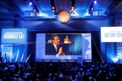 FILE - French President Emmanuel Macron appears on a screen during a live chat on Youtube and Facebook as La Republique En Marche (Republic on the Move) holds the last European election rally in Paris, France, May 24, 2019.