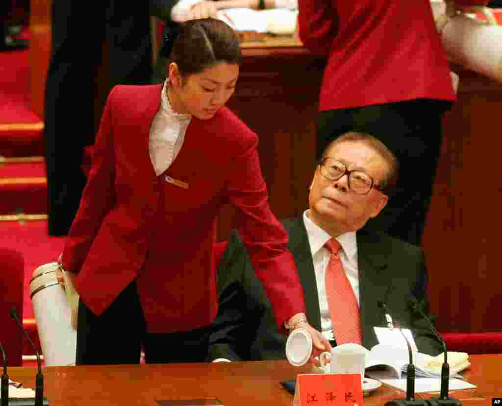2007年10月15日，在中共17大开幕式上，中国前主席江泽民看着给他送茶的女服务员