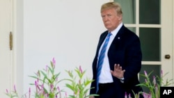 President Donald Trump waves to members of the media as he walks towards the West Wing of the White House in Washington.