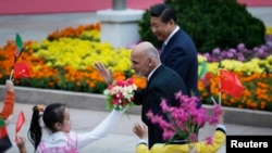 Afghanistan's President Ashraf Ghani Ahmadzai (L) waves to students as he and China's President Xi Jinping attend a welcoming ceremony outside the Great Hall of the People, in Beijing, Oct. 28, 2014.