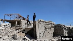 Des hommes inspectent une maison endommagée à Busra al-Harir, près de Deraa, en Syrie, le 13 mars 2018.