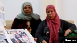 Mokhtar Hmidi, the father of Fakher, who is still unaccounted for after the capsizing of a migrant boat, shows pictures of his son, with Fakher's mother in the background, in Thina district of Sfax, Tunisia Oct. 15, 2019.