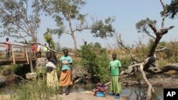 FILE - Women stand between the borders of Uganda and South Sudan near Bibi Bidi, Uganda, Dec. 11, 2016.