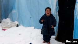 Seorang anak pengungsi Suriah menangis saat berdiri tanpa sepatu di atas salju yang turun di luar tenda penampungan di kamp pengungsi Zahle, Lembah Bekaa, Lebanon (7/1).
