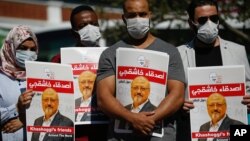 People hold posters of slain Saudi journalist Jamal Khashoggi, near the Saudi Arabia consulate in Istanbul, marking the two-year anniversary of his death, Oct. 2, 2020.