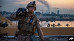 In this Saturday, Jan. 4, 2020, photo, released by the U.S. military, a U.S. Marine with 2nd Battalion, 7th Marines that is part of a quick reaction force, carries a sand bag during the reinforcement of the U.S. embassy compound in Baghdad, Iraq. (U.S. Marine Corps photo via AP)