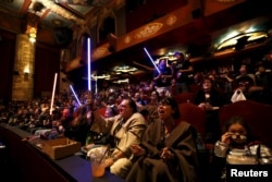 FILE - Movie-goers cheer and wave lightsabers before the first showing of the movie "Star Wars: The Force Awakens" at the TCL Chinese Theatre in Hollywood, California, Dec. 17, 2015.