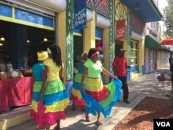 Creole dancers buy a fruit drink from a vendor at the Caribbean Marketplace in Little Haiti, Miami, Florida. (Photo: S. Lemaire / VOA)