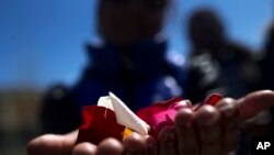 A woman holds flower petals in her hands before throwing them into the Manzanares river during an event marking the International Roma Day in Madrid, April 8, 2016. 